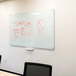 A white Aarco glass markerboard with red marker drawings on it.