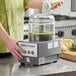 A person using a Robot Coupe food processor to prepare food on a counter.