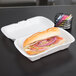 A sandwich in a Genpak white foam takeout container.