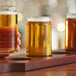 A person holding a Libbey beer tasting glass filled with beer.