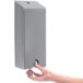 A person's hand using a GOJO ADX-12 silver security closure on a soap dispenser.