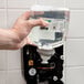 A hand using GOJO Green Certified Foam Hand Soap in a plastic bottle.