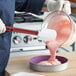 A person using a Vollrath high heat silicone spatula to mix pink substance in a bowl.