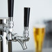 A black plastic Avantco beer tap handle on a silver and black tap.