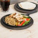 A Lodge cast iron griddle with chicken, rice, and vegetables on a table.