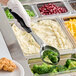 A person using a Vollrath black solid oval spoodle to serve broccoli and mashed potatoes.