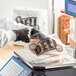 A person in black gloves using a Choice Deli Saddle Bag Stand to weigh food in a plastic bag with a logo on it.