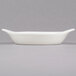 A CAC bone white stoneware shirred egg dish on a gray surface.