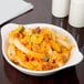 A CAC bone white stoneware shirred egg dish filled with french fries, cheese, and jalapenos.