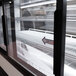 A close-up of a white curved glass door on a refrigerated deli case.