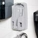 A grey plastic GOJO manual hand soap dispenser on a white tile wall.