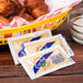 A basket of food with Crystal hot sauce packets and condiments.