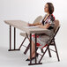 A woman sitting at a Correll seminar folding table writing in a book.