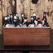 An American Metalcraft copper rectangular metal container filled with bottles of beer on a table.