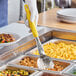 A person using a Vollrath Jacob's Pride heavy-duty perforated basting spoon with a yellow handle to serve food.