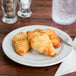 A Carlisle melamine bread and butter plate with two croissants on it.