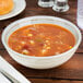 A Carlisle Grove melamine bowl filled with soup, corn, and beans on a table.