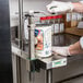 A person in a white lab coat using a Garde standard-duty manual can opener on a can.