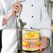 A chef using a Garde manual can opener to open a can of cheese sauce.