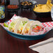 A blue HS Inc. oval deli server filled with a group of tacos with meat and lettuce on a table.