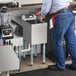 A man standing at a Regency underbar hand sink in a professional kitchen.