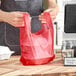 A man holding a red plastic bag.