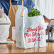 A person holding a plastic bag with a bunch of greens.