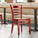 A Lancaster Table & Seating mahogany wood ladder back chair with mahogany wood seat in a restaurant.