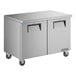 A stainless steel True undercounter freezer with black handles on wheels.