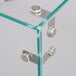 A clear glass sneeze guard with metal screws.