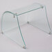 A curved glass sneeze guard on a clear glass shelf.