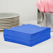 A stack of cobalt blue Creative Converting luncheon napkins.