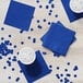 A blue Creative Converting beverage napkin on a table with blue cups and ice.