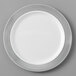 A white plastic plate with a silver lattice design on the border.
