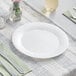 A Visions Wave white plastic plate with a knife and fork on it.