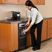 A woman using a Follett 7 Series undercounter ice maker and water dispenser to fill a cup with water.