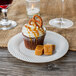 A cupcake on a Visions Wave bone plastic plate with a pretzel on top.