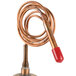 A copper water regulator with a red handle.