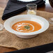 A Visions Wave plastic bowl of soup on a table.