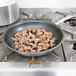 A Vollrath stainless steel non-stick fry pan with meat cooking in it.