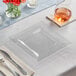 A Visions clear square plastic plate with silverware on a table.