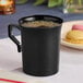 A black plastic coffee mug filled with coffee.