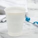 A Dart translucent plastic cup filled with water on a marble counter with a toothbrush.