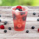 A Dart translucent plastic cup filled with fruit and berries and ice cubes.