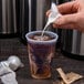 A hand pouring white liquid into a Dart translucent plastic cup.