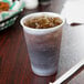 A Dart Conex plastic cup filled with a brown liquid and ice.