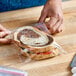 A hand wrapping a sandwich in a plastic bag.