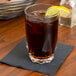 An Arcoroc highball glass of ice tea with a lemon wedge on a napkin.