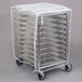 A metal sheet pan rack with white plastic cover and metal trays on it.