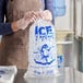 A clear plastic bag filled with ice, featuring blue printed text and a cartoon character, labeled as an 8 lb. ice bag.
